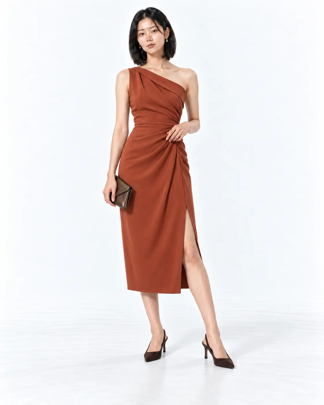 Copper Draped Fall Wedding Guest Dress Woman in a copper one-shoulder draped midi dress with brown slingback heels on a white studio background.