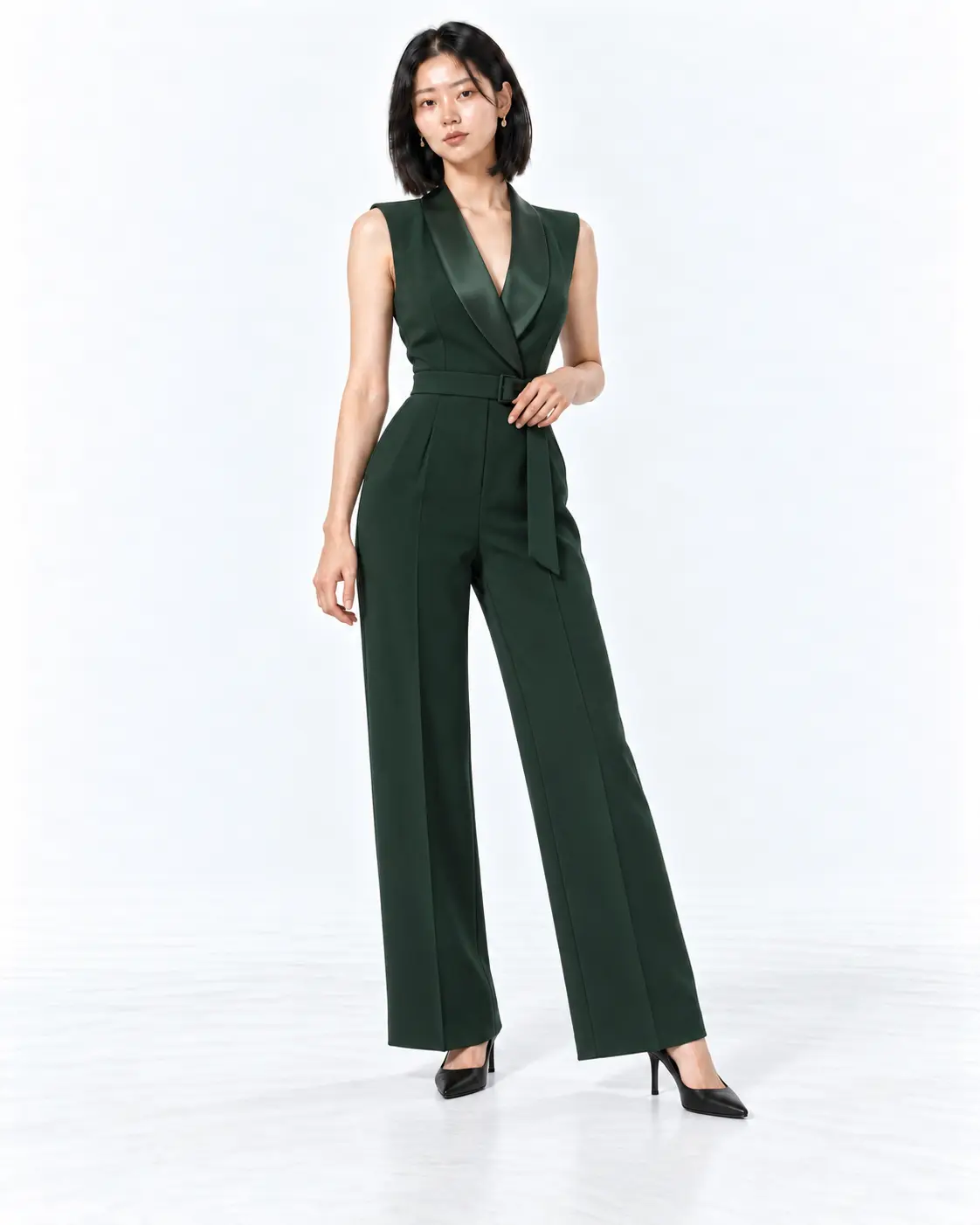 Forest Green Wedding Guest Tuxedo Jumpsuit Woman wearing a forest green tuxedo jumpsuit with a satin collar and black pointed pumps in a white studio.