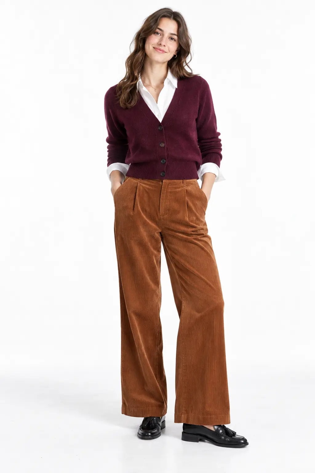 Plum Cardigan and Corduroy Trousers Full-body white-studio image of a woman wearing plum cardigan; white poplin shirt; cinnamon corduroy trousers; tassel loafers.