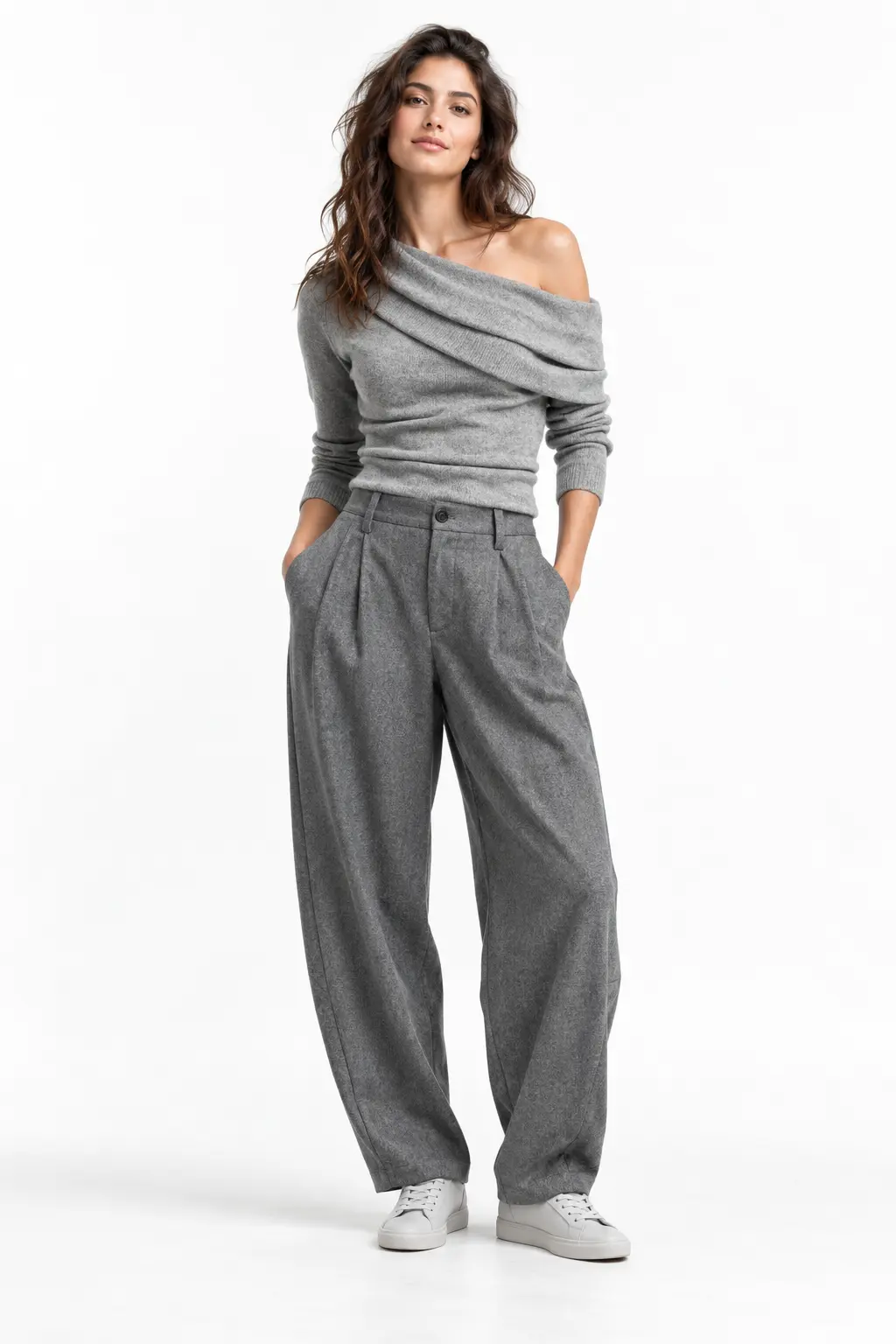 Grey Draped Knit and Barrel Trousers Full-body white-studio image of a woman wearing grey asymmetric knit top; grey barrel trousers; light-grey sneakers.