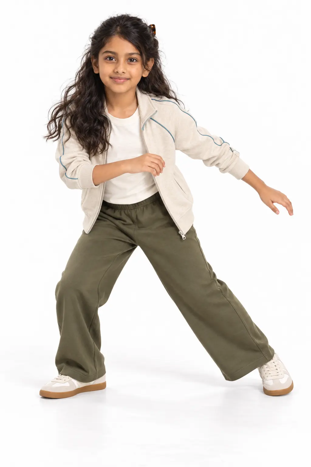 Girls' Sporty Track Jacket and Wide-Leg Pants Outfit Girl in a cream zip-up track jacket with blue piping, olive wide-leg pants and white sneakers, posing playfully.