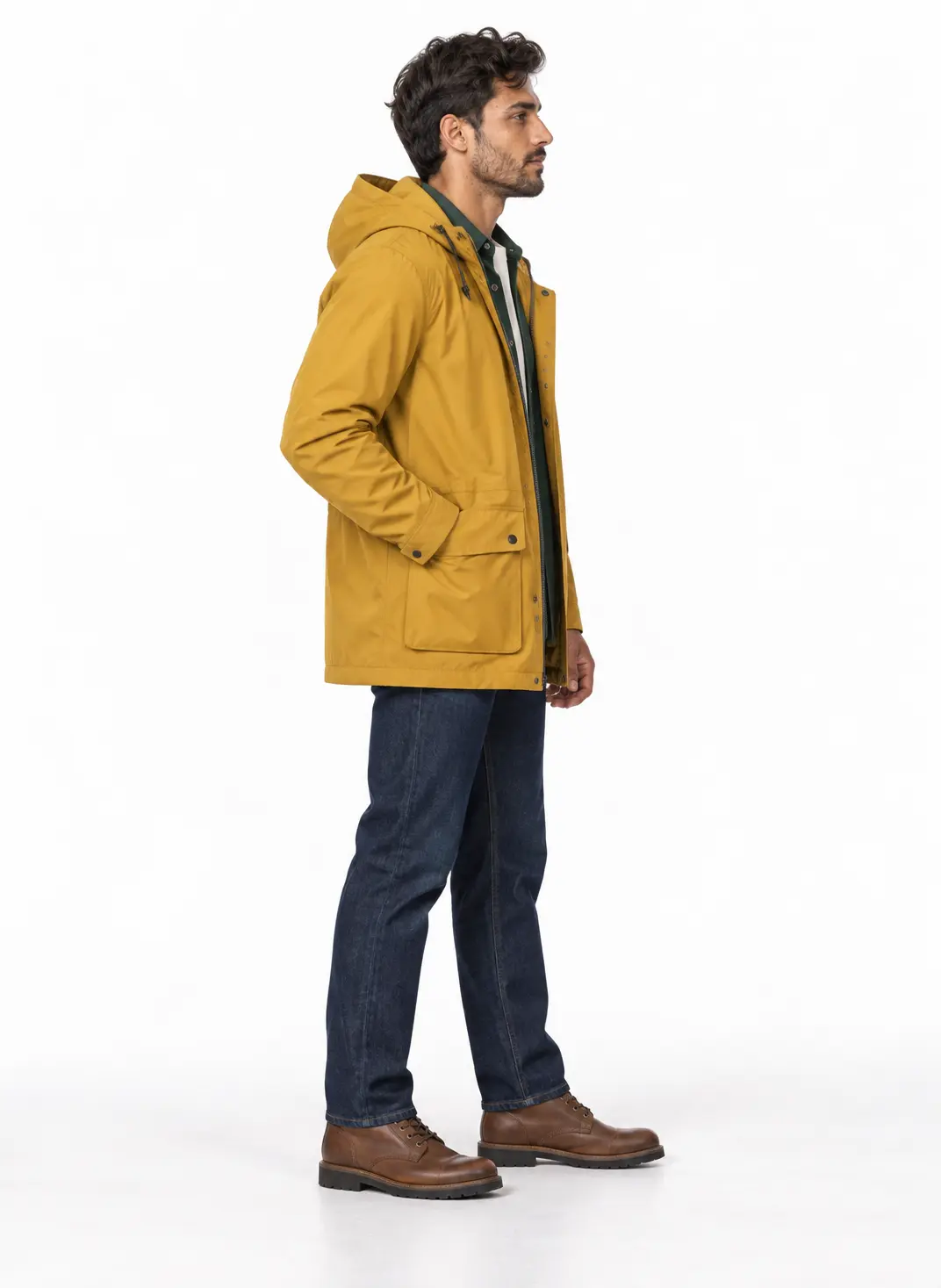 Men's Saffron Parka Rain Outfit A man standing in profile wearing a saffron yellow hooded parka, dark blue jeans, and brown leather boots.