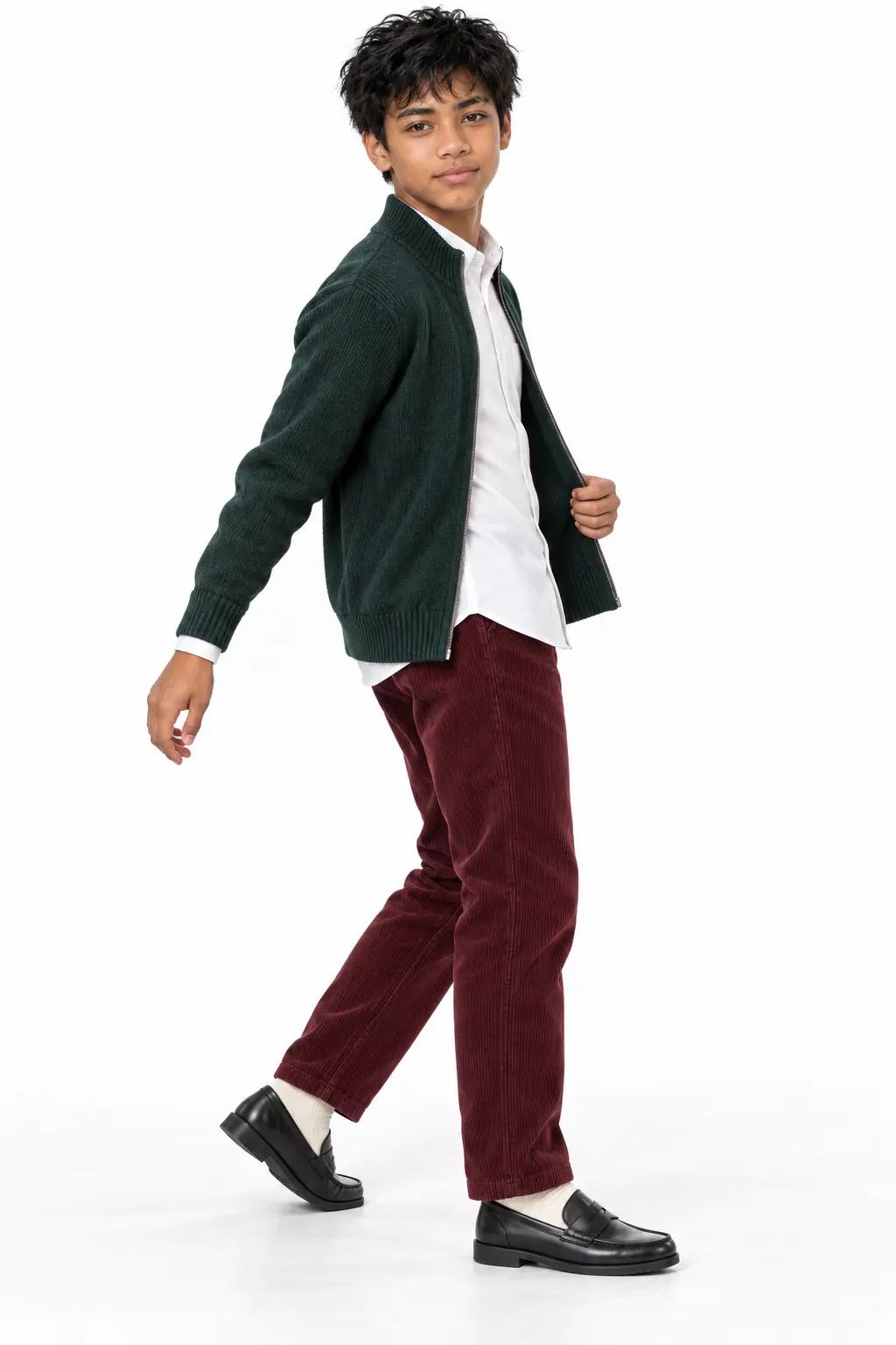 Teen Boy Wearing Pine Green Knit Zip Cardigan and Burgundy Corduroy Pants A teenage boy in a studio setting wearing a dark pine green zip-up knit cardigan over a white collared shirt, paired with burgundy corduroy pants and black leather loafers.